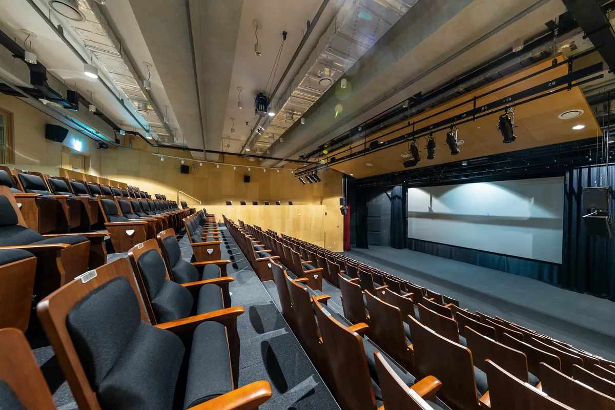 寬敞的空 auditorium，有木製座椅和投影幕布在現代環境中。