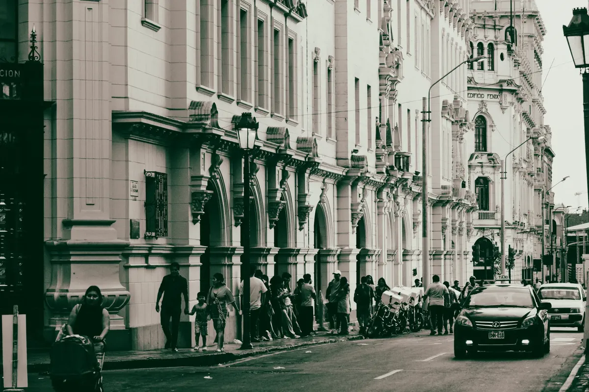 Street view of historic architecture with people and cars in a bustling city scene.