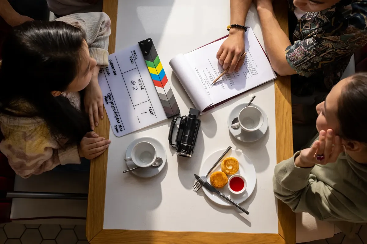 Aerial view of a team discussing a project with a clapperboard in a café setting.