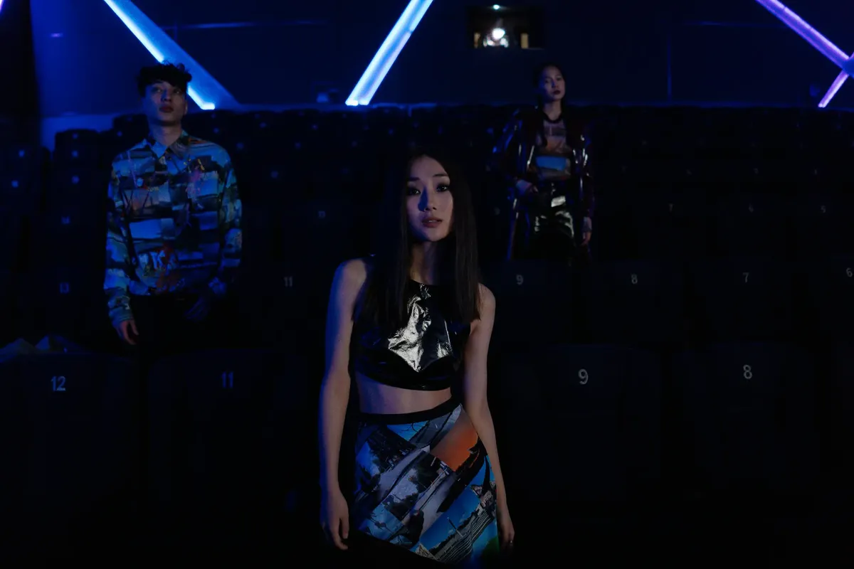 Stylish individuals pose in a dimly lit cinema highlighting vibrant fashion.