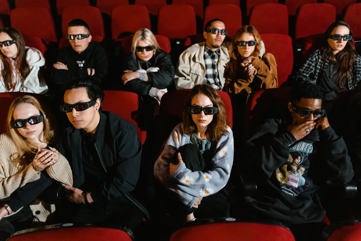 A diverse group of people wearing 3D glasses, immersed in a movie inside a theater.