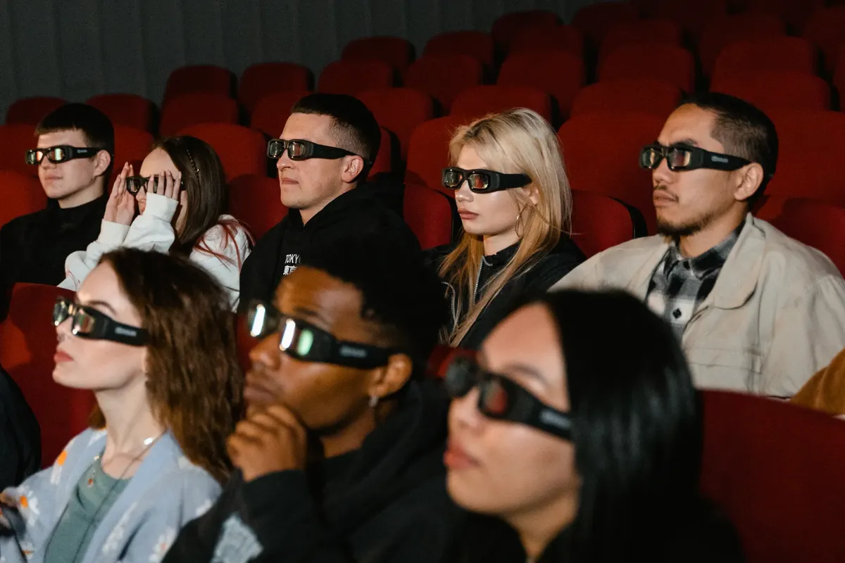 多様な年齢層の成人が劇場での3D映画体験を楽しんでいる。