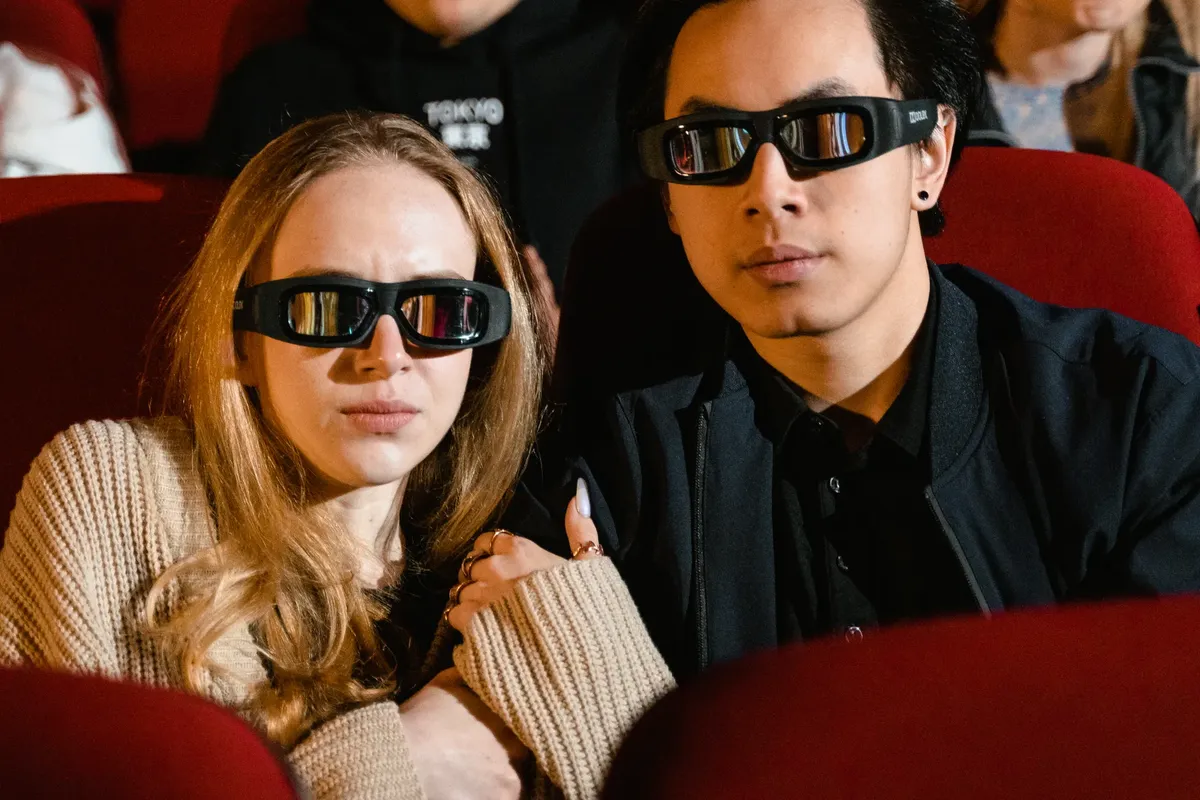 カップルがリラックスした劇場で3D映画を一緒に見ている。