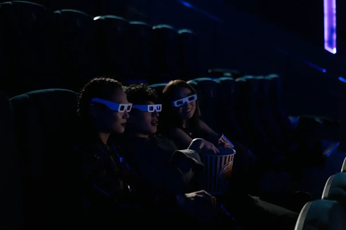 一群朋友佩戴3D眼罩，在影院內觀看電影，並享用薯片。