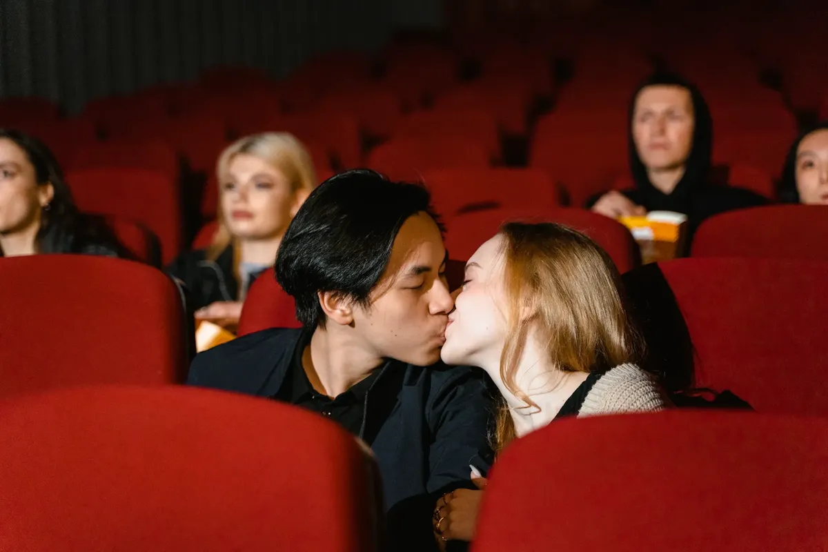 Romantic couple kissing in a cozy movie theater setting.
