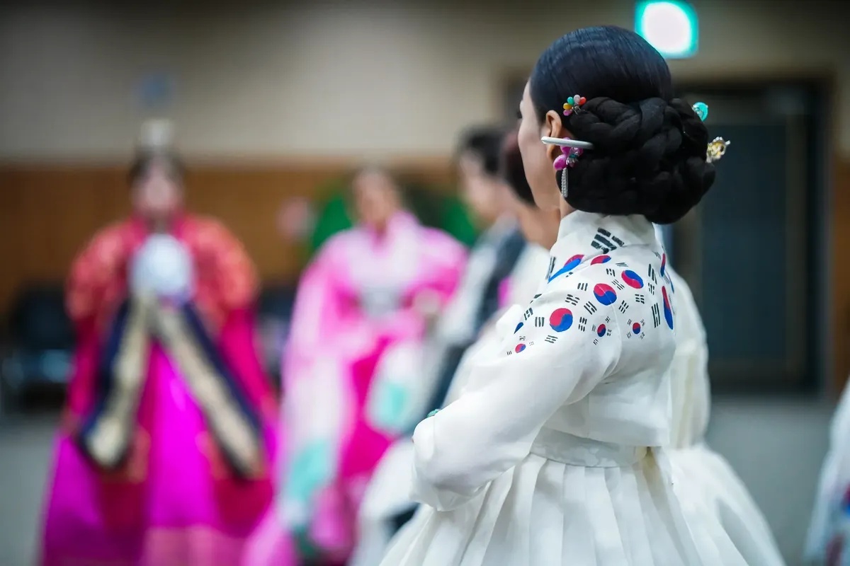 Elegant Korean woman in traditional hanbok during a cultural event indoors.