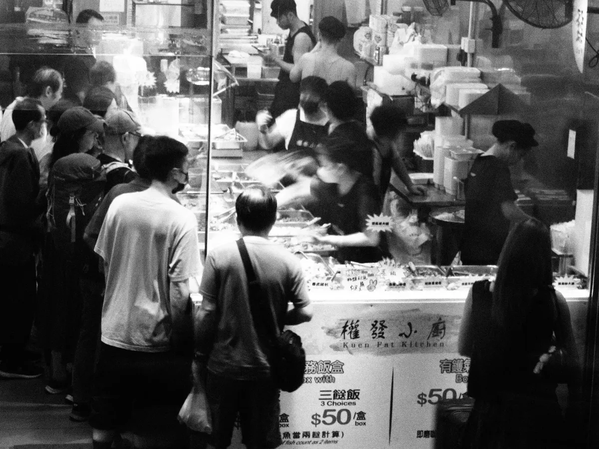 香港一間忙碌的街頭小吃攤位，人們正排隊等候。