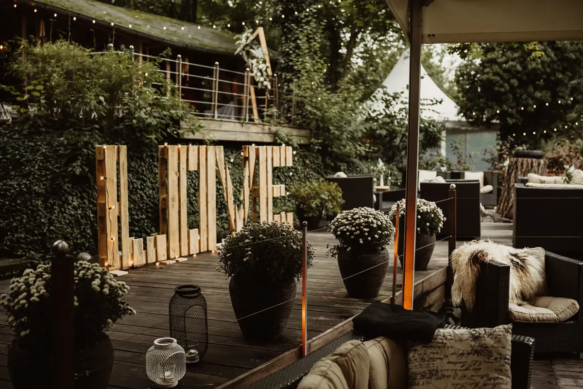 Warm and inviting outdoor space with a large 'LOVE' sign, charming lighting, and plush seating.
