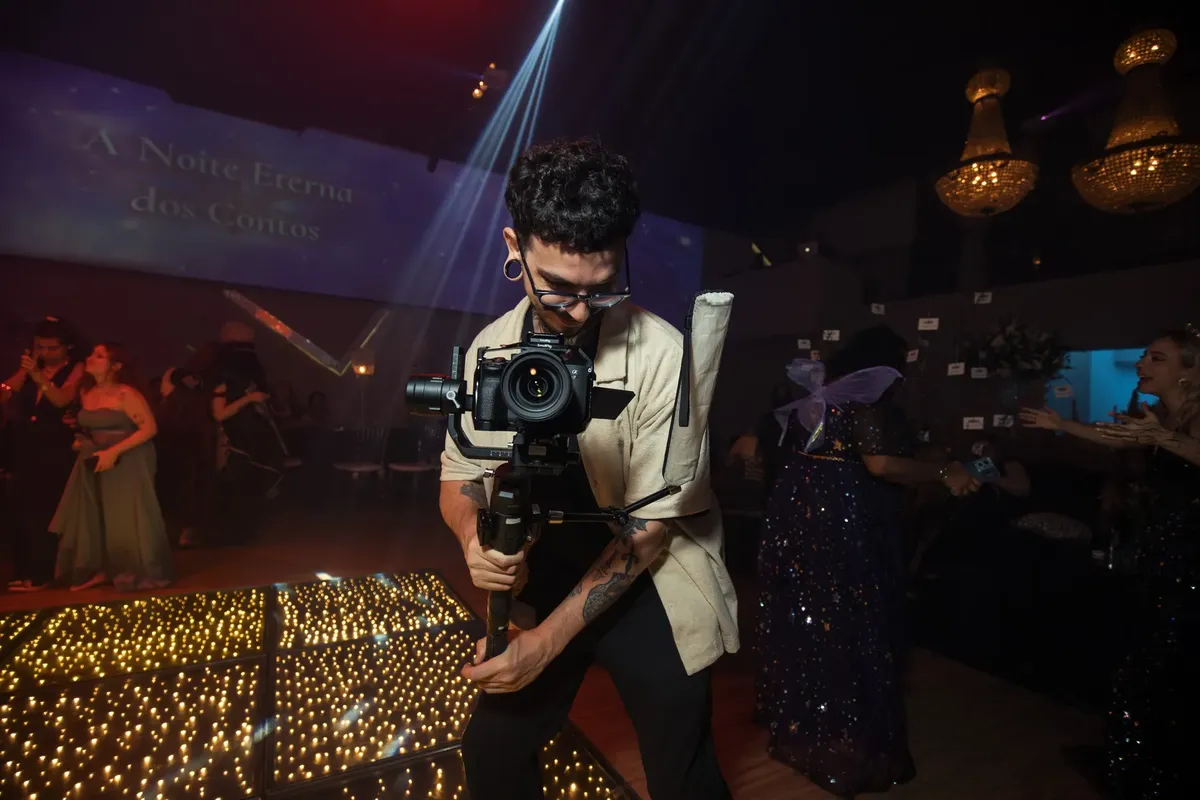 A skilled photographer filming an elegant party with vibrant lighting and dressed-up guests.