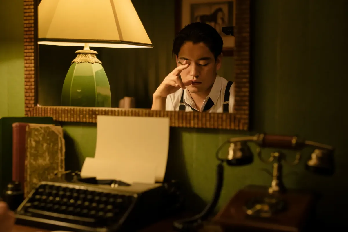 A vintage-themed scene with an Asian man in reflection, featuring a typewriter and lamp.