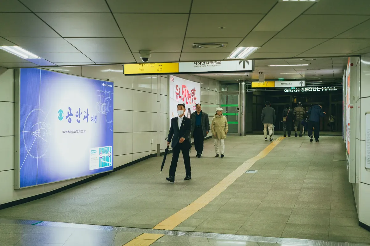 ソウルの電車駅で通勤中の人々が、南韓の都市生活と建築を展示している。
