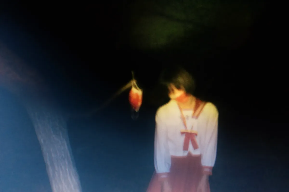 Blurred image of a person in dim light, creating a mysterious and dreamy atmosphere.