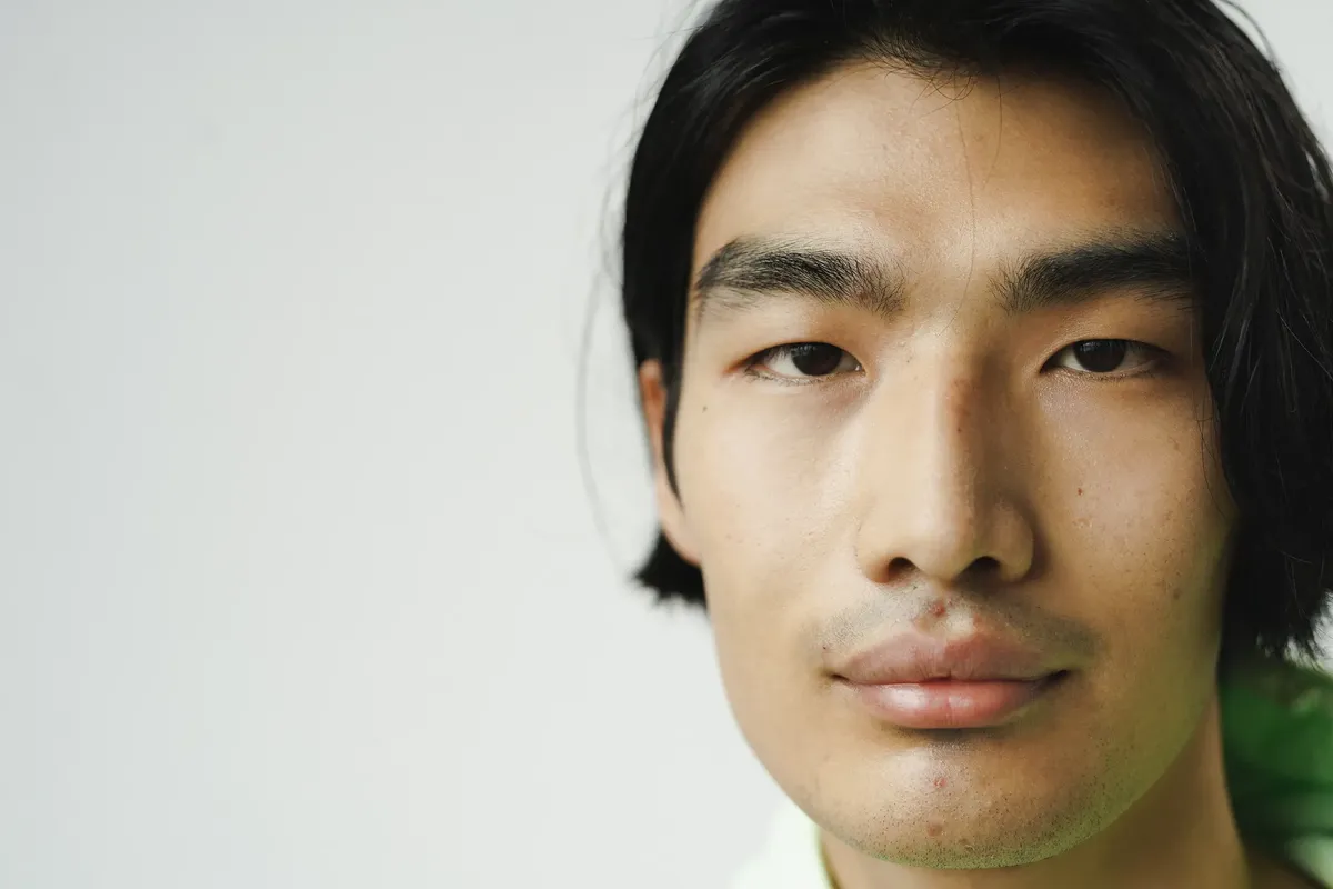 Close-up headshot of a serious Asian man in a studio setting.
