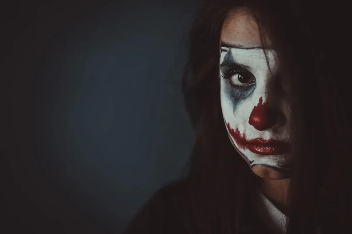 モodyな女性のポートレート。クローン風のメイクが、創造的なメイクとハロウィンテーマを表現している。