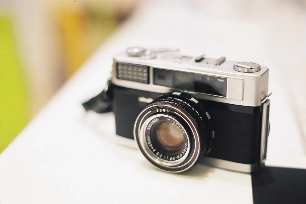 Close-up of an elegant silver and black vintage 35mm film camera on a white surface.