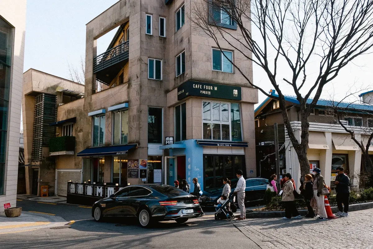Urban street view with people and a cafe, showcasing a lively neighborhood atmosphere.