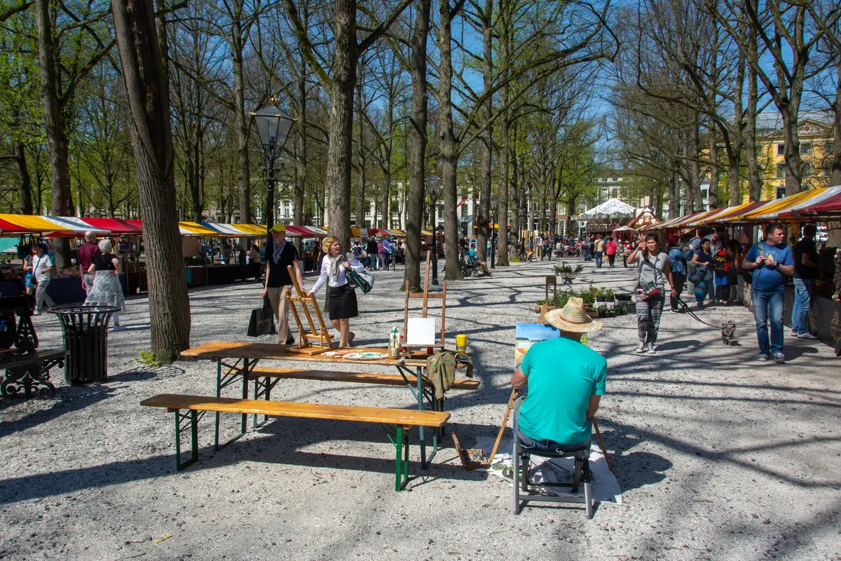 Lively scene at an outdoor art market in Den Haag, showcasing artists and vendors.
