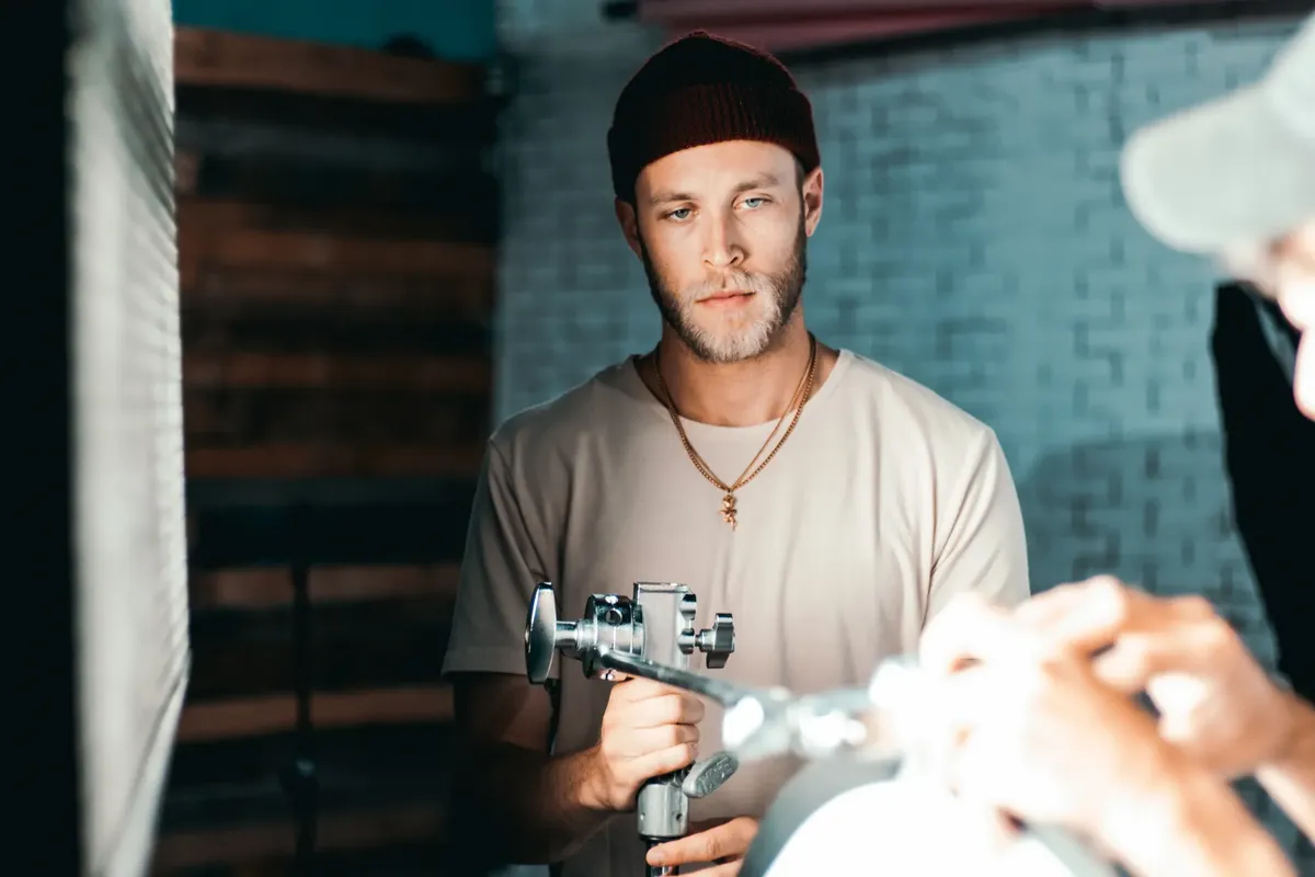 Professional filmmaker holding camera equipment in a studio setting.