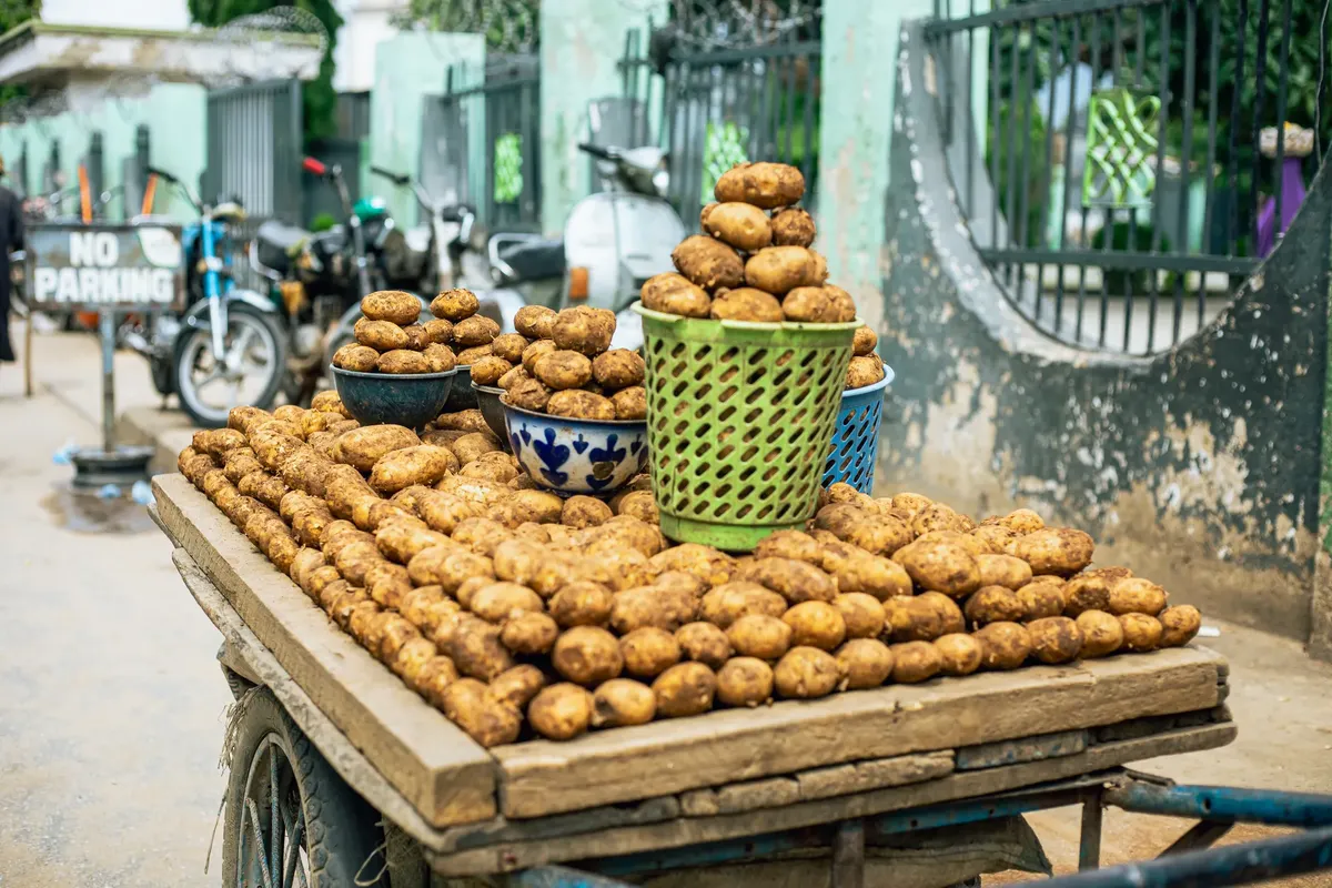 Fresh potatoes on a street cart in Nigeria's vibrant market setting.