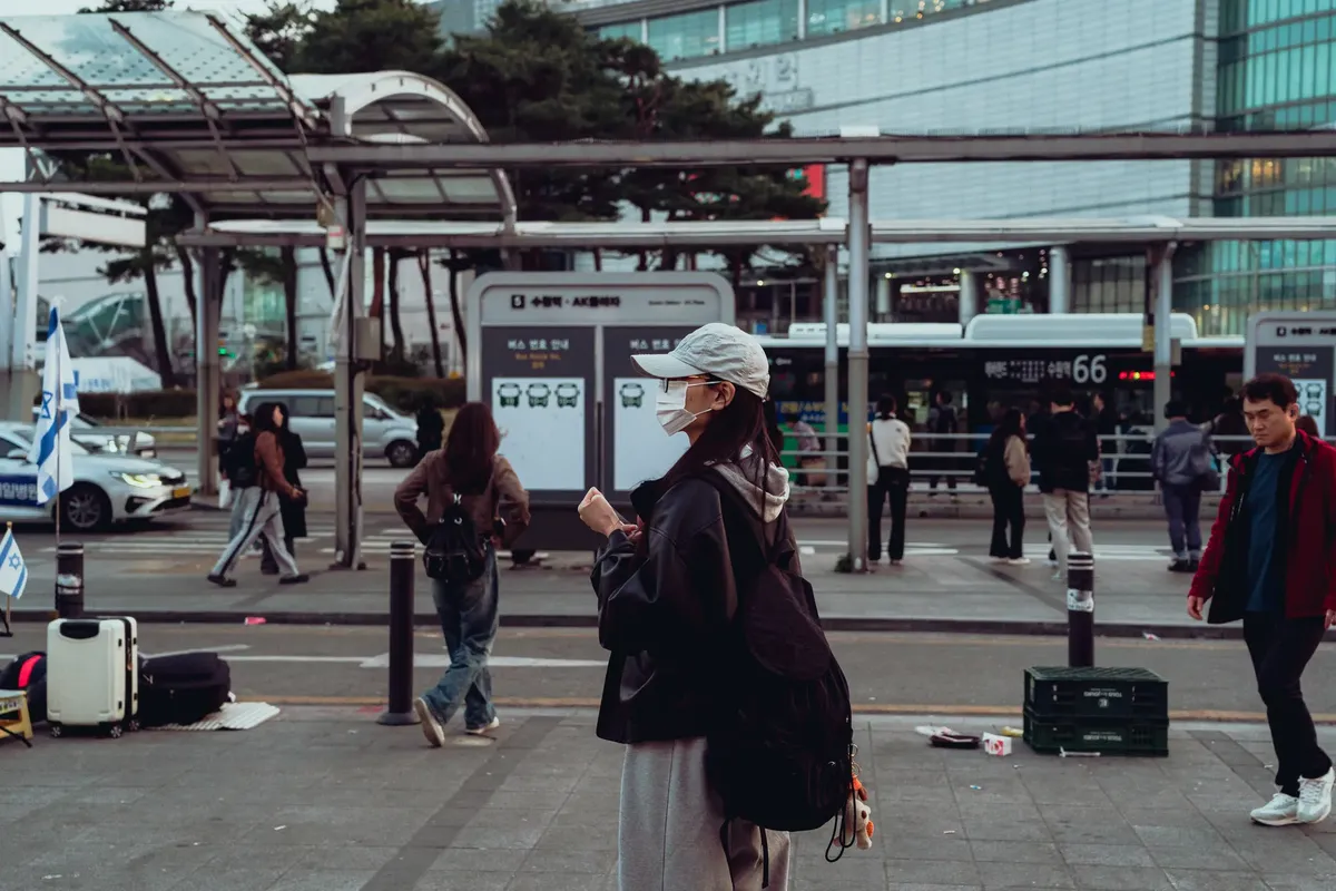 A casual street view in Suwon-si showing people and public transport.