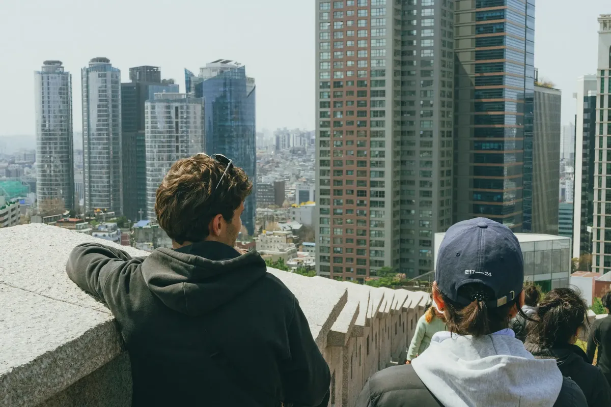 People observing the modern Seoul skyline from an elevated viewpoint.