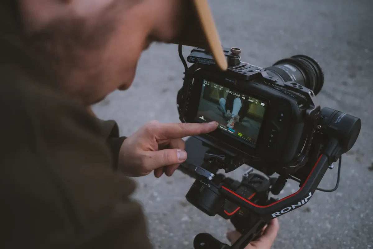 Camera operator reviewing footage on a screen with focus on filmmaking equipment.