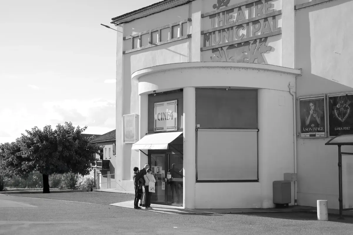 Retro theater entrance with patrons in black and white, evokes a classic cinematic feel.