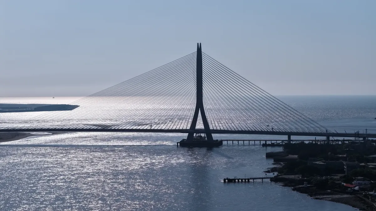 一張壯麗的空中視圖，展示台北淡水河橋的現代設計，背景是閃爍的海景。