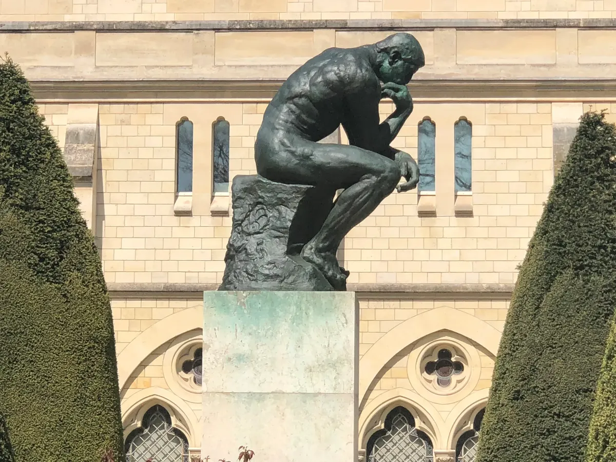 The iconic Thinker statue in Paris in front of a historic building.