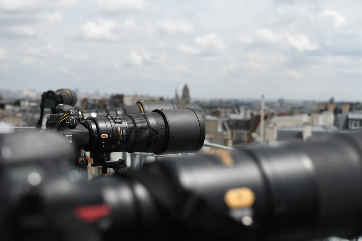 Telephoto lenses focus over Paris, capturing the iconic skyline with DSLR cameras.
