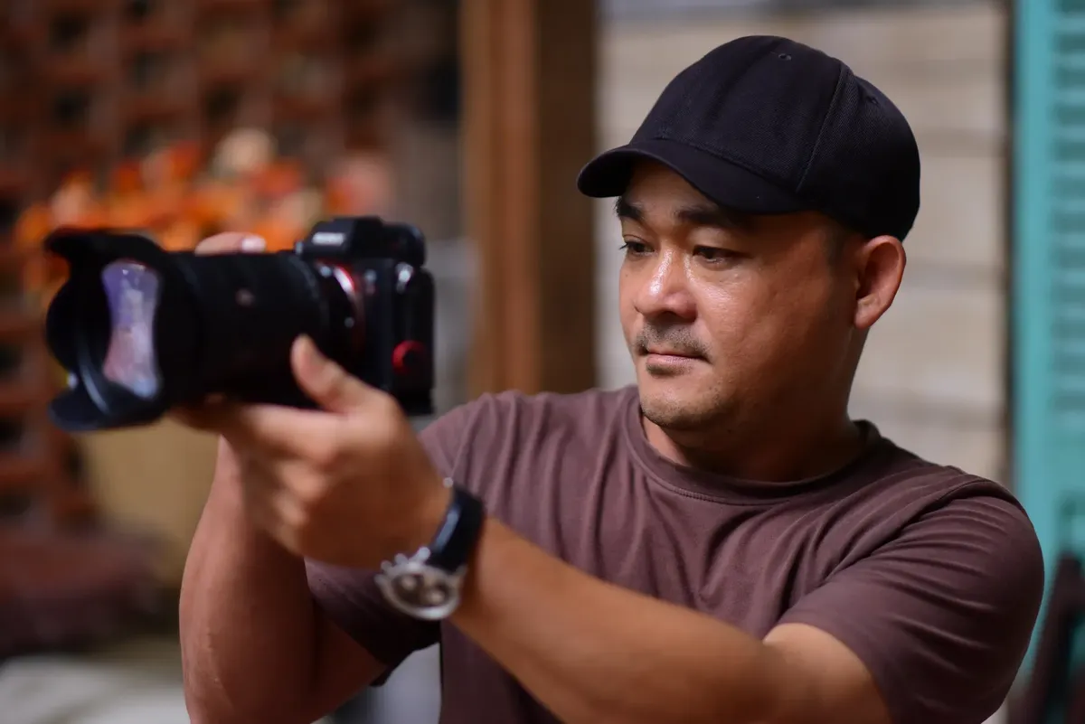 캐주얼한 옷을 입은 남자 촬영자가 실내에서 DSLR 카메라를 사용하고 있습니다. 집중하고 전문적인 모습입니다.