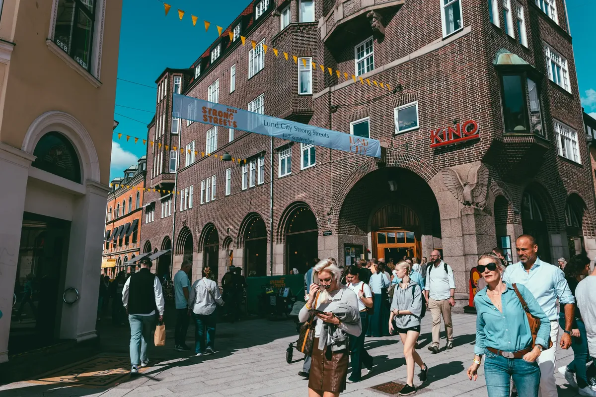 A bustling street in Lund, Sweden with people walking by iconic architecture.