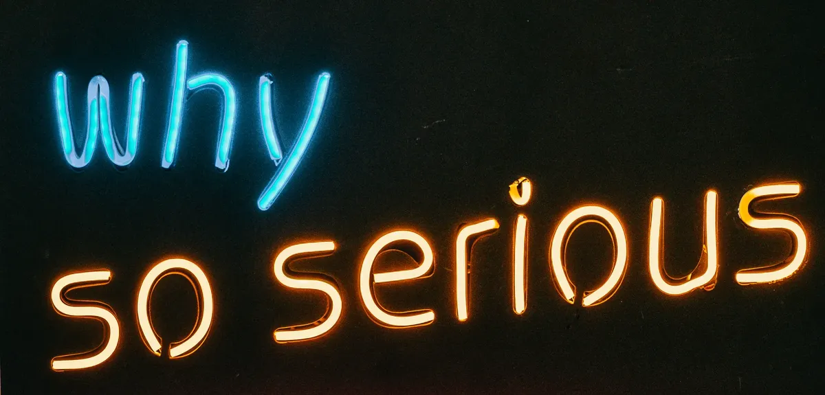 Vibrant neon sign displaying 'Why So Serious' text against a dark background.