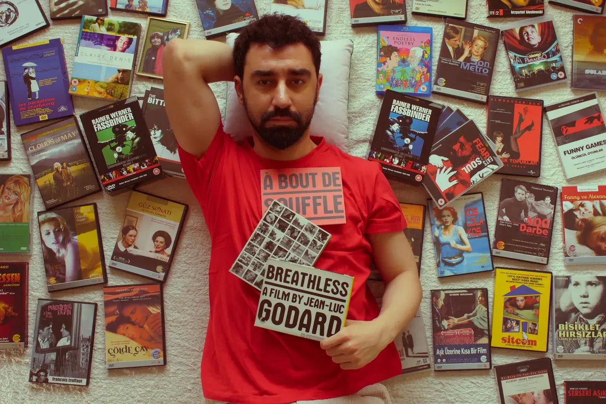 A man lies among various movie DVDs, highlighting his extensive collection and love for films.