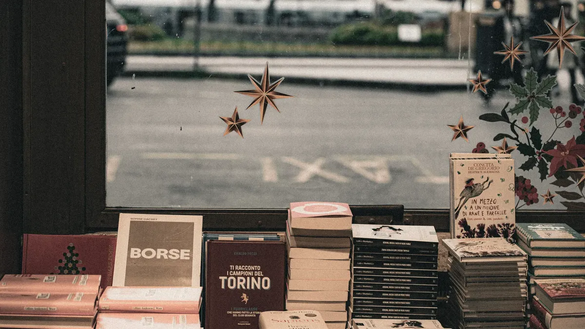 A charming bookshop window display featuring stacked books and festive decor.