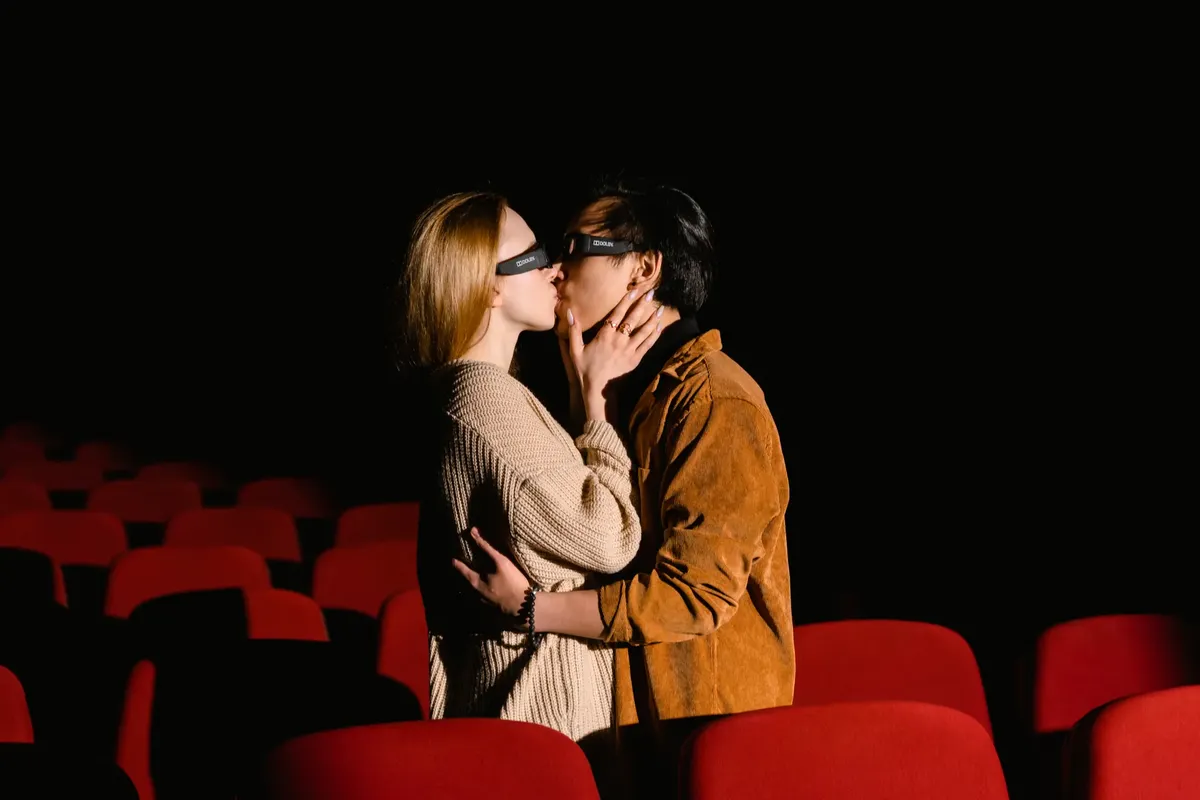 A couple sharing a romantic moment while wearing 3D glasses in an empty cinema.