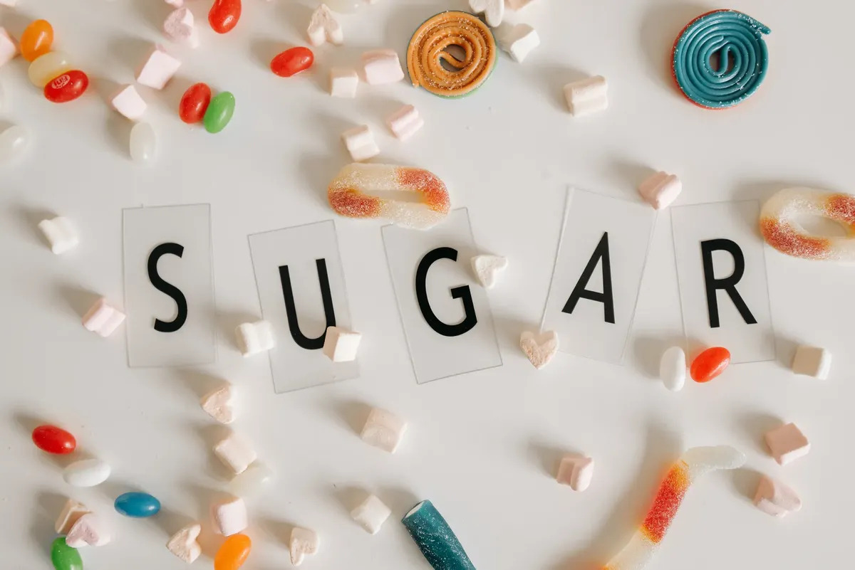 白底上散落著各色糖果的平鋪佈置，周圍有「SUGAR」字样。